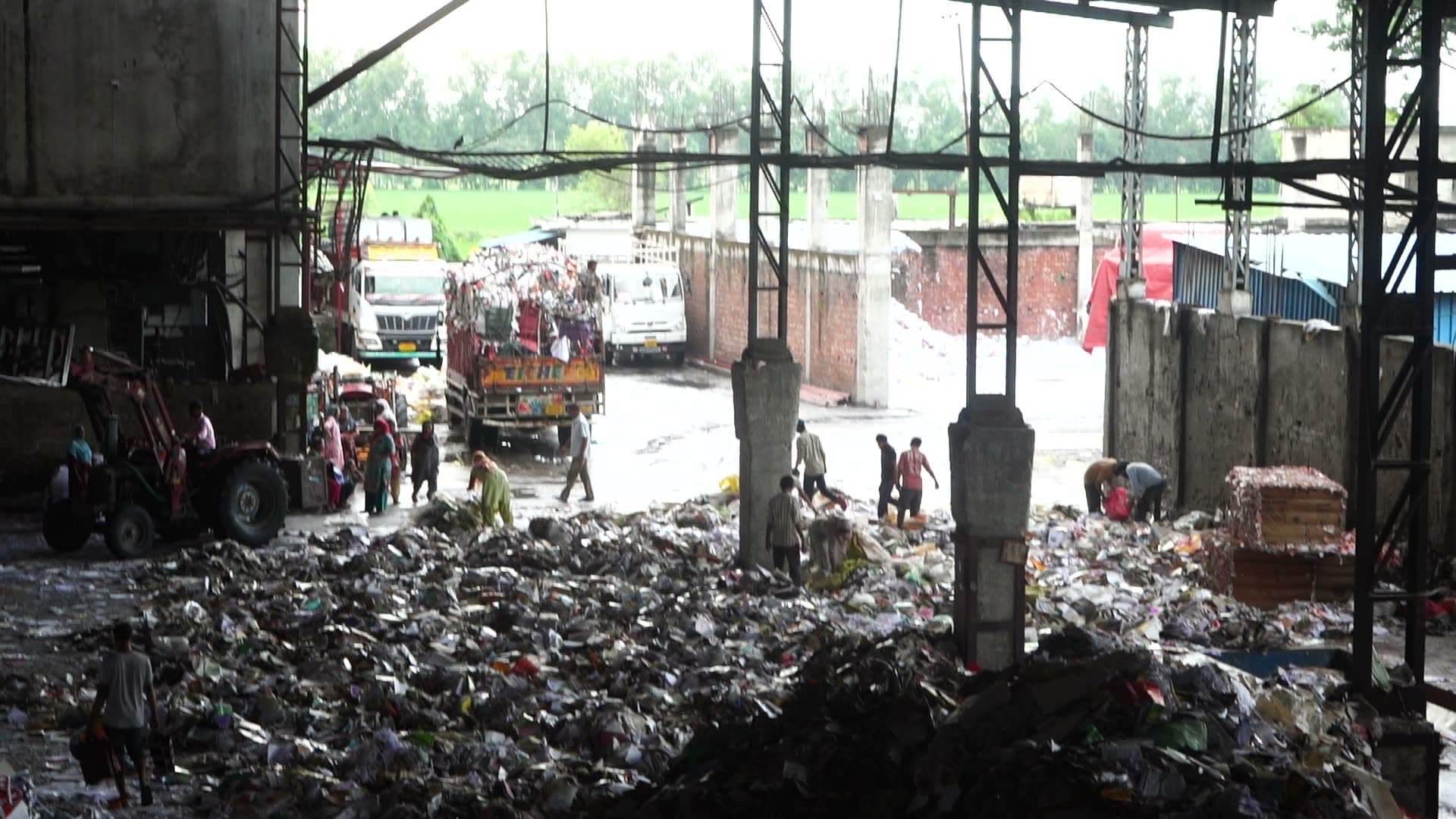 Intake yard at Katyayini Mills — trucks unloading and crew working the recovered-paper heap